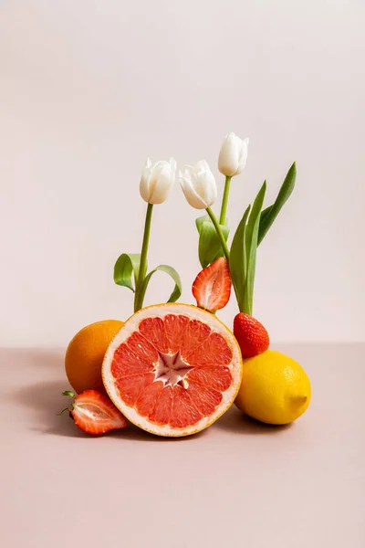 Floral and fruit composition with tulips and summer fruits isolated on beige — Stock Photo