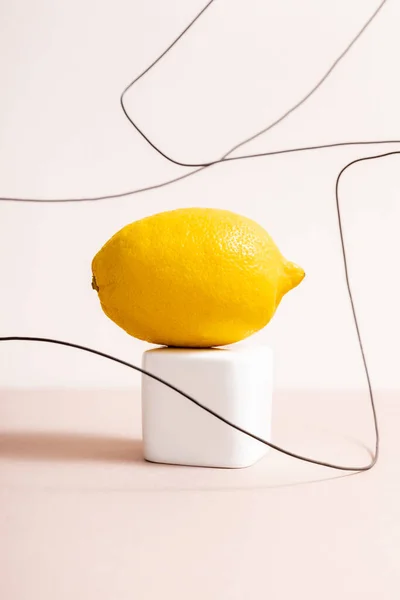 Lemon on cube and wire isolated on beige — Stock Photo