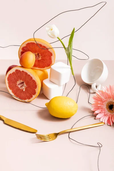 Composition florale et fruitée avec tulipe, gerbera, fruits, couverts, tasse isolée sur beige — Photo de stock