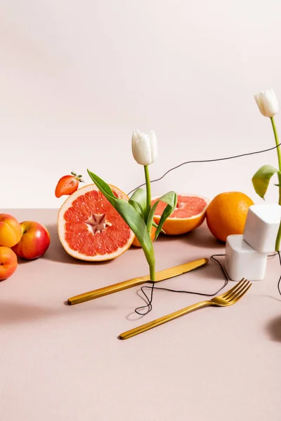 Composizione floreale e fruttata con tulipani, frutta, posate isolate su beige — Foto stock