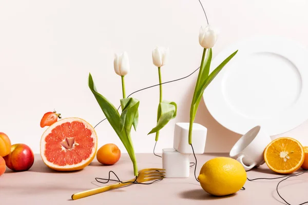 Composition florale et fruitée avec tulipes, fruits, vaisselle isolée sur beige — Photo de stock
