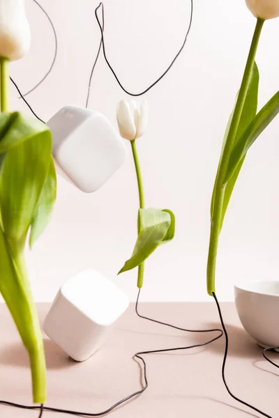 Selektiver Fokus der kreativen floralen Komposition mit Tulpen auf Drähten, Tasse und quadratischen Würfeln isoliert auf Beige — Stockfoto