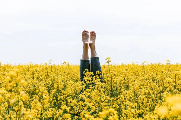 Vista recortada de mujer descalza cerca de flores amarillas en el campo - foto de stock