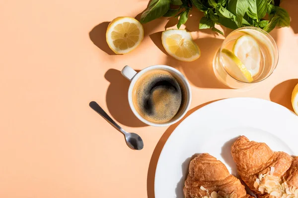 Vista superior de la taza de café y croissants para el desayuno en la mesa beige - foto de stock