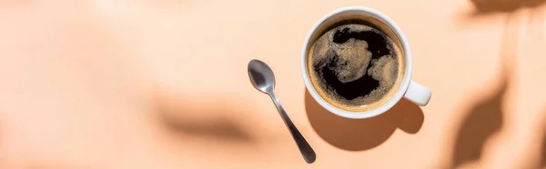 Top view of coffee cup and teaspoon on beige with shadows, horizontal concept — Stock Photo