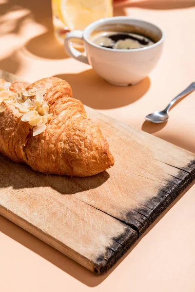 Croissants frescos na tábua de corte e xícara de café no café da manhã na mesa bege — Fotografia de Stock