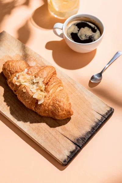 Cruasanes frescos sobre tabla de madera y taza de café para el desayuno sobre mesa beige - foto de stock