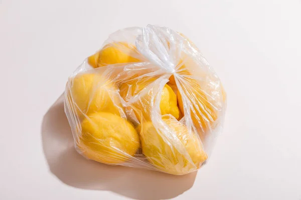 Fresh yellow lemons in plastic bag on grey table — Stock Photo