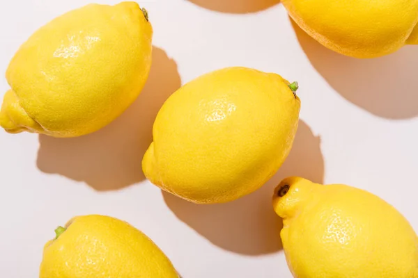 Primer plano de limones maduros enteros sobre una mesa gris con sombras - foto de stock