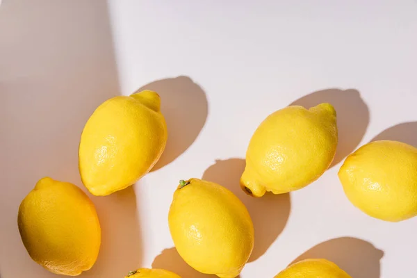 Draufsicht auf ganze gelbe Zitronen auf grauen Tisch mit Schatten — Stockfoto