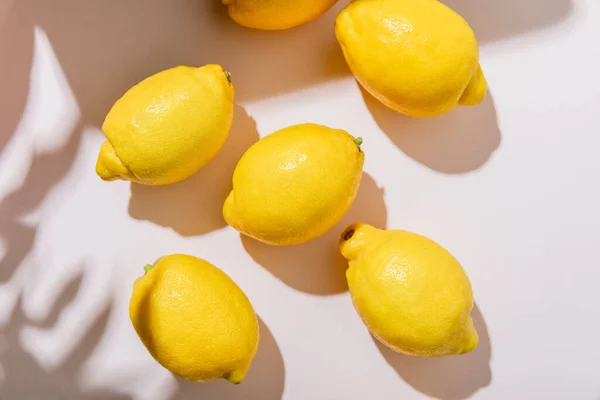 Вид зверху на цілі жовті лимони на сірому столі з тінями — стокове фото