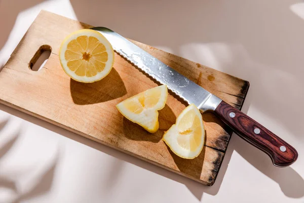 Limone tagliato a fette su tavola di legno su tavolo grigio con ombre — Foto stock