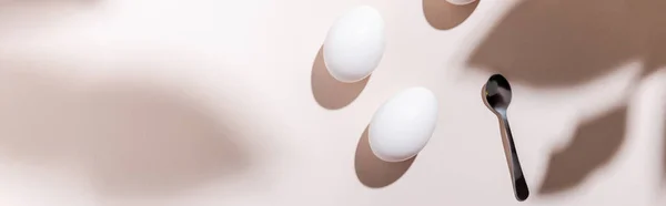 Top view of white boiled chicken eggs and teaspoon on grey table with shadows, website header — Stock Photo