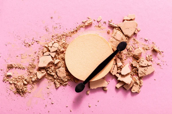 Vista superior do aplicador de sombra dupla face perto de pó de rosto rachado e esponja de maquiagem em rosa — Fotografia de Stock