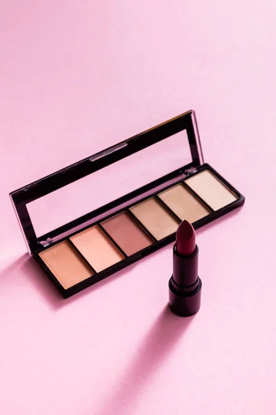 Eye shadow palette near lipstick on pink — Stock Photo