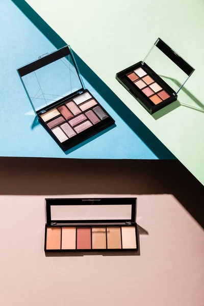 Eye shadow palettes on blue, green and pink — Stock Photo