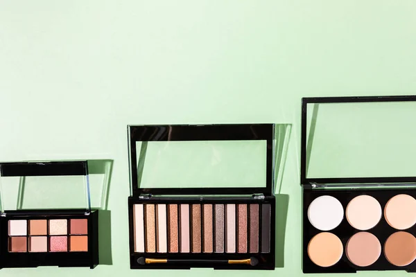 Top view of eye shadow and blush palettes on green — Stock Photo