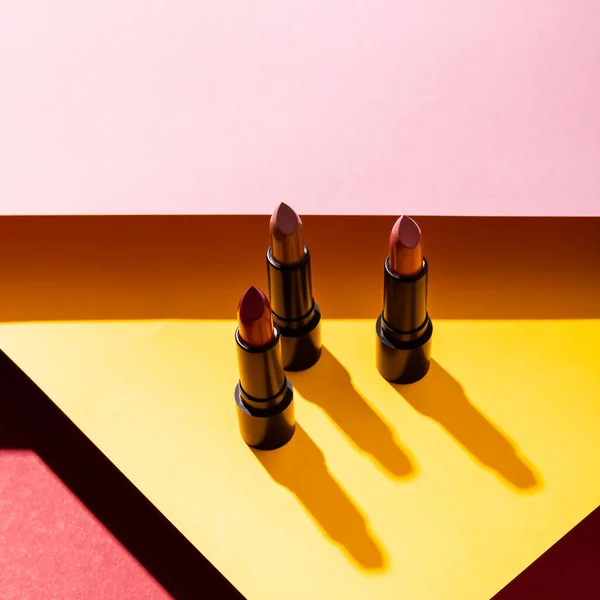 Primer plano de los lápices labiales en amarillo, carmesí y rosa - foto de stock