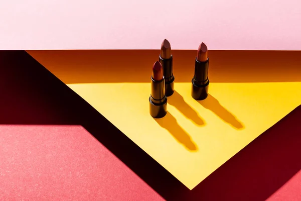 Sombras perto de batons em amarelo, rosa e carmesim — Fotografia de Stock