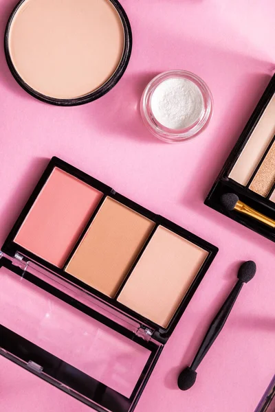 Top view of face powder and blush near eye shadow palette on pink — Stock Photo