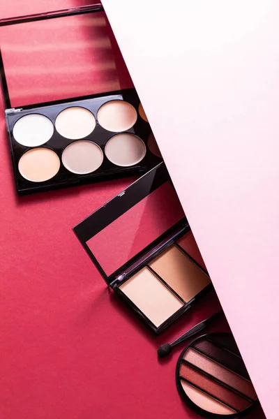 Pastel eye shadow and blush palettes on pink and crimson — Stock Photo