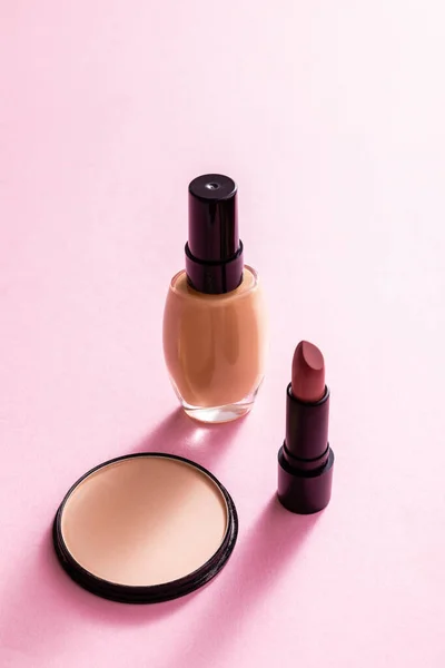 Face powder near lipstick and makeup foundation on pink — Stock Photo