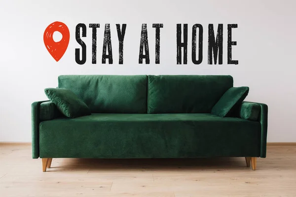 Moderno sofá verde con almohadas cerca de la estancia en casa lettering - foto de stock