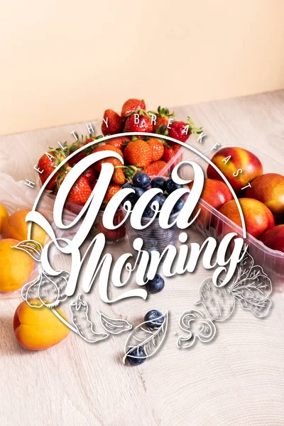 Blueberries, strawberries, nectarines and peaches in plastic containers near good morning lettering on beige — Stock Photo