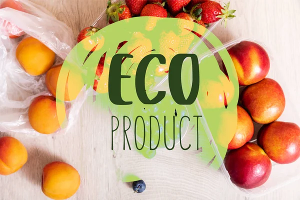 Top view of fruit composition with blueberries, strawberries and nectarines in plastic containers near eco product lettering on wooden surface — Stock Photo