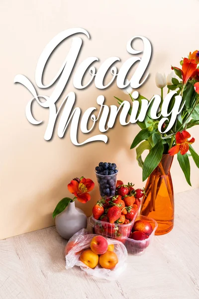 Blumenkomposition mit Blumen in Vasen in der Nähe von Früchten und Guten Morgen Schriftzug auf beige — Stockfoto