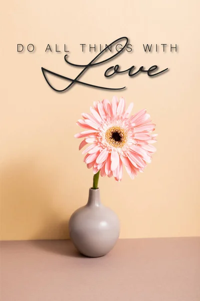 Pink gerbera in vase near do all things with love lettering on beige — Stock Photo