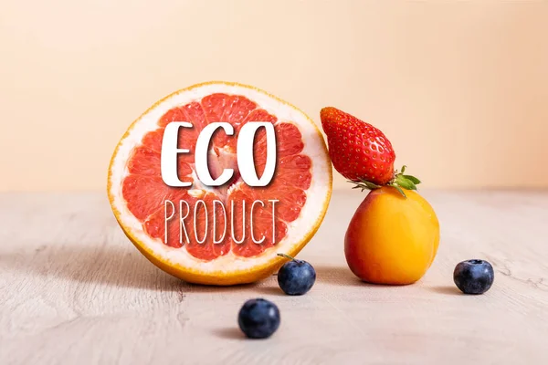 Fruit composition with berries, grapefruit and apricot near eco product lettering on beige — Stock Photo