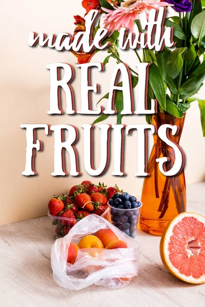 Blüten- und Fruchtkomposition mit Beeren, Grapefruit und Aprikosen in der Nähe mit echten Früchten Schriftzug auf beige — Stockfoto