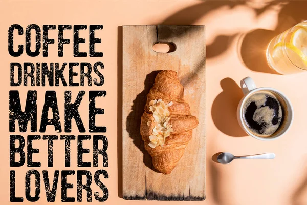 Vista superior de café, agua y croissant en tablero de madera para el desayuno en la mesa beige con los bebedores de café hacen mejores amantes letras - foto de stock