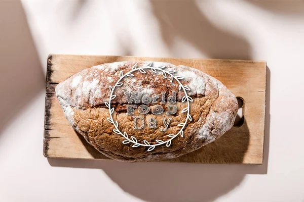 Top view of bread on cutting board on grey table with world food day lettering — Stock Photo