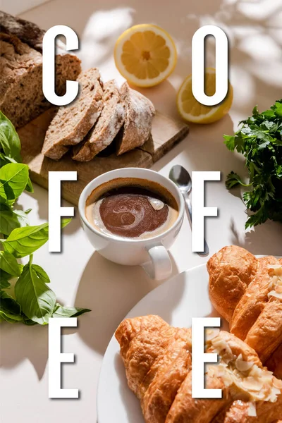 Cruasanes frescos, pan, vegetación y taza para el desayuno en la mesa gris con letras de café - foto de stock