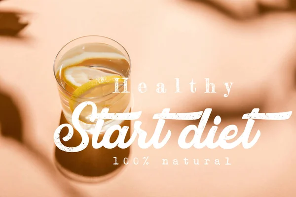 Glass of fresh water with lemon slices on beige with healthy start diet 100 percents natural lettering — Stock Photo