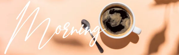 Верхний вид чашки кофе и чайной ложки на бежевый цвет с утренней надписью, заголовок сайта — стоковое фото