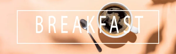 Ansicht von Kaffeetasse und Teelöffel auf Beige mit Frühstücksaufdruck, horizontales Konzept — Stockfoto