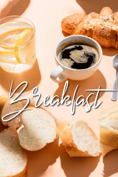 Tasse de café, croissant, eau et baguette sur table beige avec lettrage petit déjeuner — Photo de stock