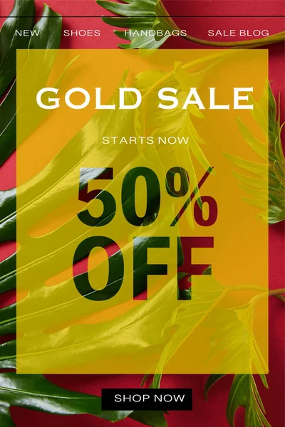 Vista superior de hojas verdes tropicales sobre fondo rojo con ilustración de venta de oro - foto de stock