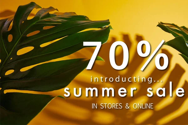 Vista superior de hojas verdes tropicales sobre fondo amarillo con ilustración de venta de verano - foto de stock