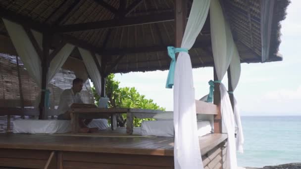 Hombre Feliz Sentado Gazebo Trabajando Ordenador Con Vistas Mar Marco — Vídeos de Stock