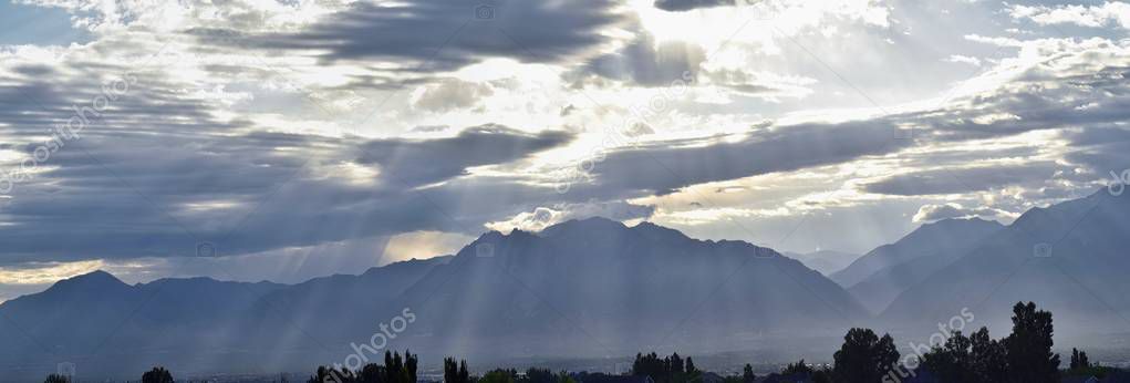 Panoramic misty view of angel rays from Sunrise and the Wasatch Front Rocky Mountain range looking East in Salt Lake City Utah in Utah, USA.