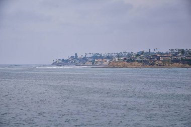 San Diego, iskeleler, İskelesi ve kum, sörfçü, uyarı işaretleri, palmiye ağaçları, dalgalar, kaya, tekneler ve ufuk sayısı da dahil olmak üzere çevresinde görev plaj görüntüleyin. Pasifik Okyanusu. California, Amerika Birleşik Devletleri.