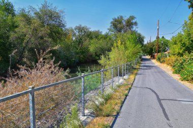 Ağaçlar, Rusya zeytin, cottonwood ve silt çevreleyen ile görünümlerini Ürdün Nehri Trail çamurlu su boyunca Wasatch açık Rocky Dağları, Salt Lake City, Utah dolu.