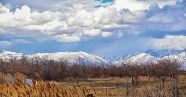 Winter Panoramic view of Snow capped Wasatch Front Rocky Mountains, Great Salt Lake Valley and Cloudscape from the Bacchus Highway. Utah, USA. clipart