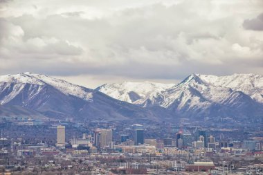 Şehir Merkezi Salt Lake şehir panoramik görünüm Wasatch Front Rocky Dağları kar ve bulutluk erime ile erken ilkbahar kış uçakta. Utah, Amerika Birleşik Devletleri.