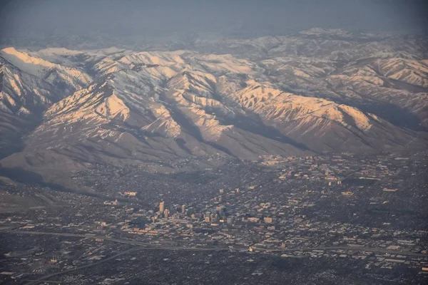 プロボ ファーミントンバウンティフル オレム ソルトレイクシティの都市を含む冬の雪のピークを持つワサッチフロントロッキー山脈の飛行機からの航空写真 — ストック写真