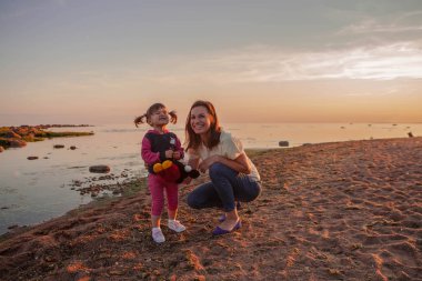 Anne ve kızı gün batımında sahilde yürüyüş. Mutlu bir dostu aile kavramı.